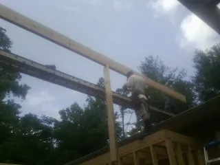 Carpenter setting a ridge beam over a new addition frame — Ice Dam Removal by Roofing Brothers in Bohannon