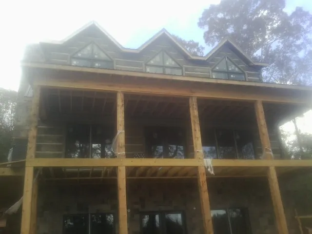 Dormers and porch framing on a large log home under construction — Roof Coating work by our crew in Bohannon