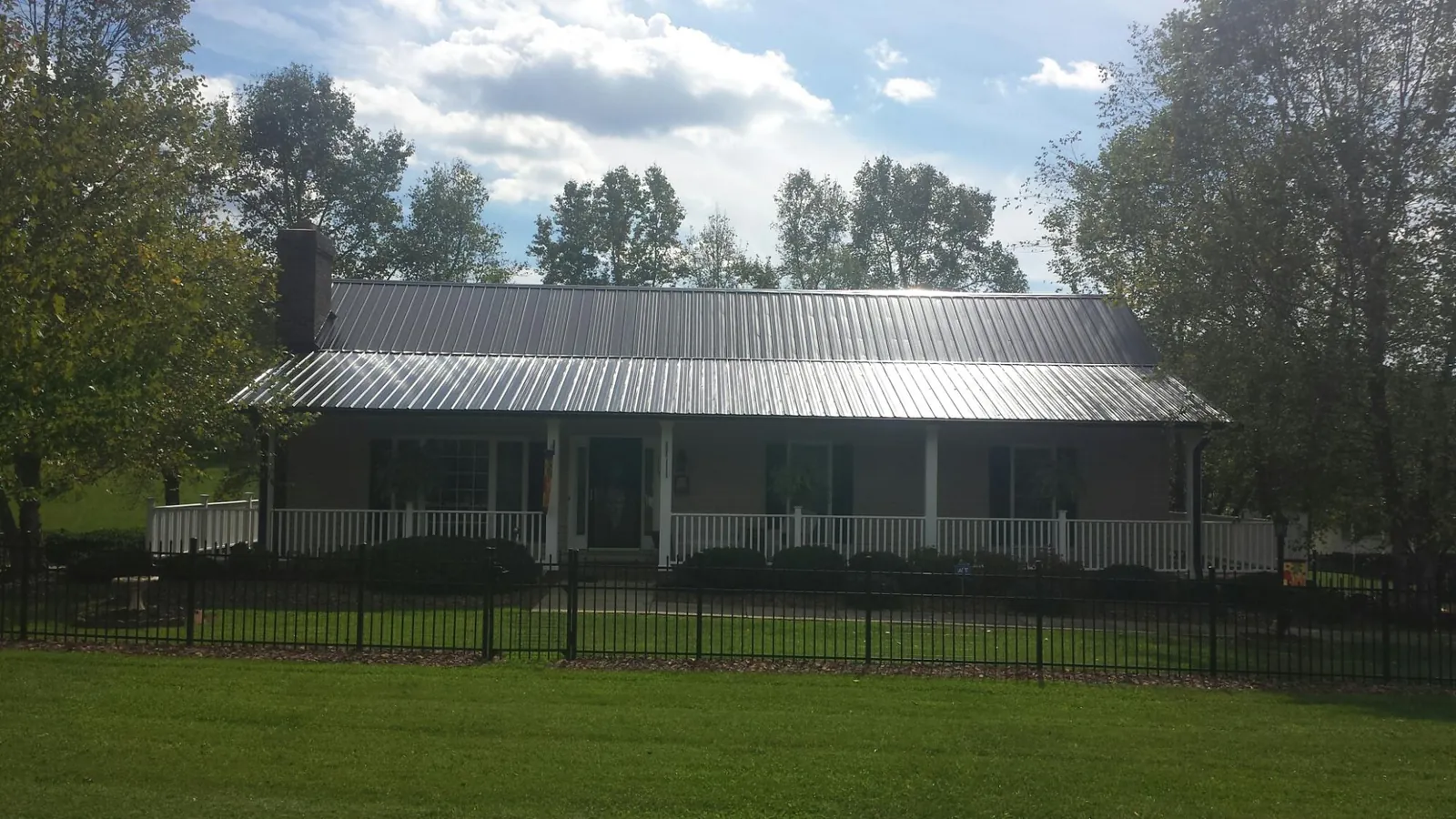 Gray metal roof on a brick ranch with a full width front porch — Gutter Guard Installation work by our crew in Bohannon