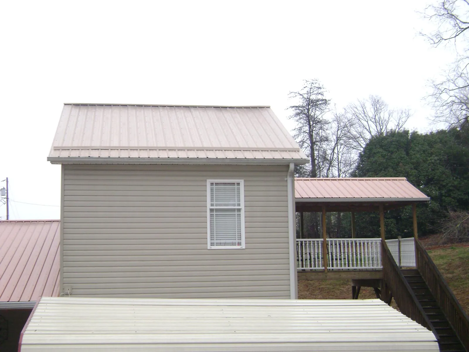 Tan metal roofs on a two story addition and attached porch, from a Roof Replacement job in Bohannon