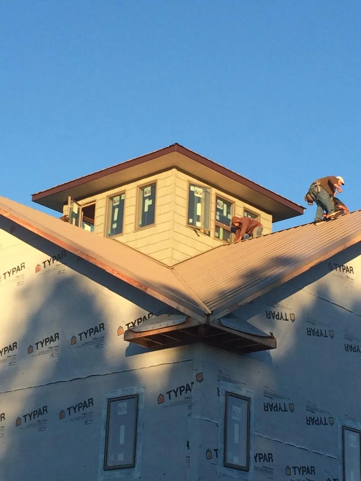 Roofers working around a rooftop cupola on a new metal roof at sunset — Roof Waterproofing in Bohannon by Roofing Brothers
